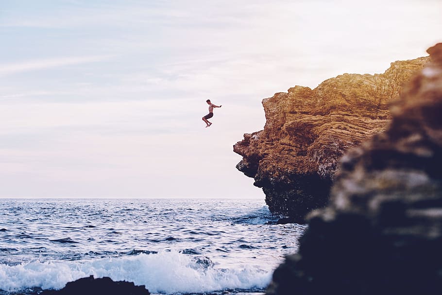 person jumping to body of water during daytime, man jumped from cliff to body of water, HD wallpaper