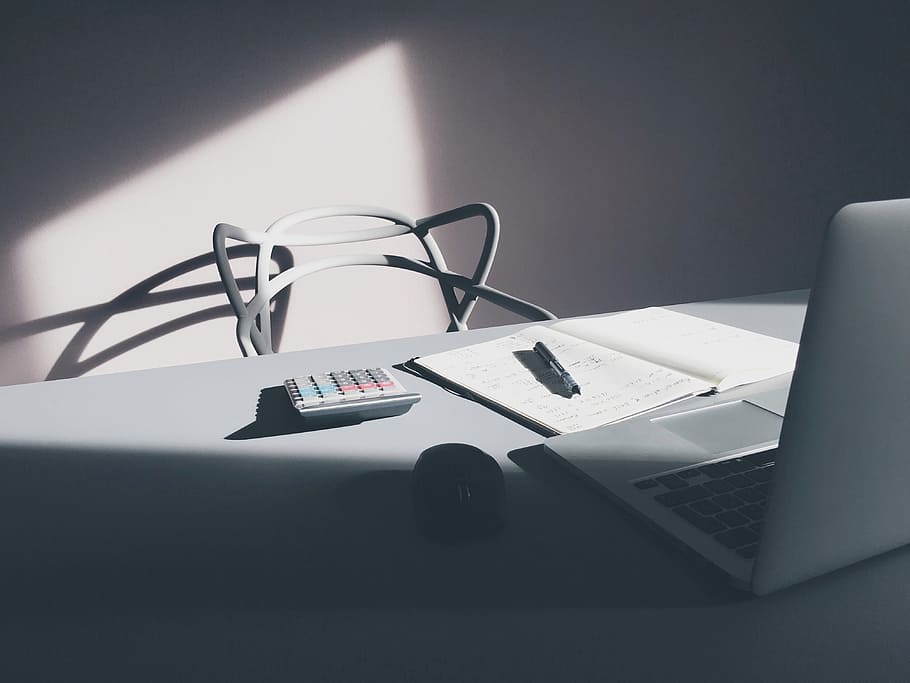 gray calculator near silver laptop computer and computer mouse on wooden table, unoccupied gray chair beside table HD wallpaper