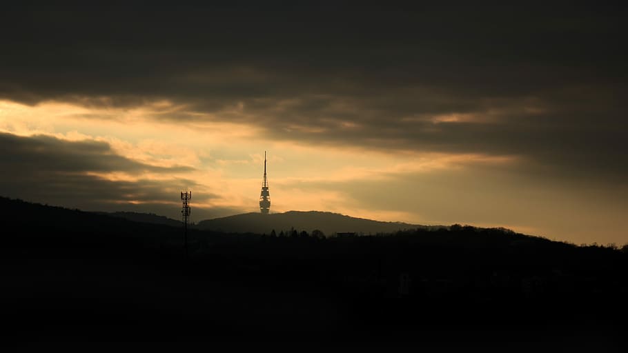 black tower under clouds, silhouette of mountain under gray cloudy sky HD wallpaper