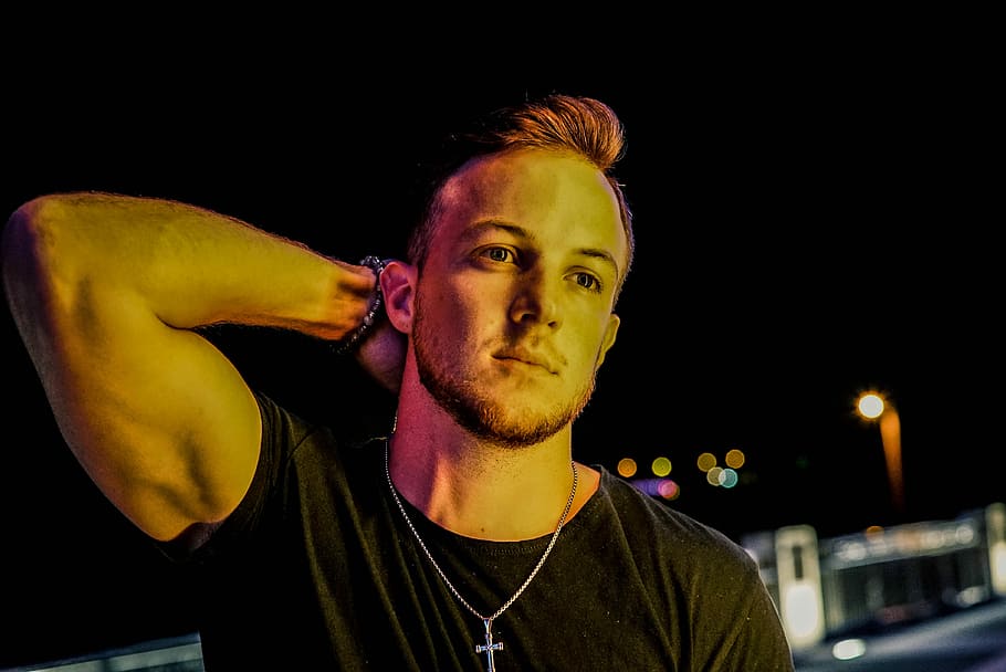 men's black crew-neck T-shirt, man wearing black shirt standing near building during nighttime HD wallpaper