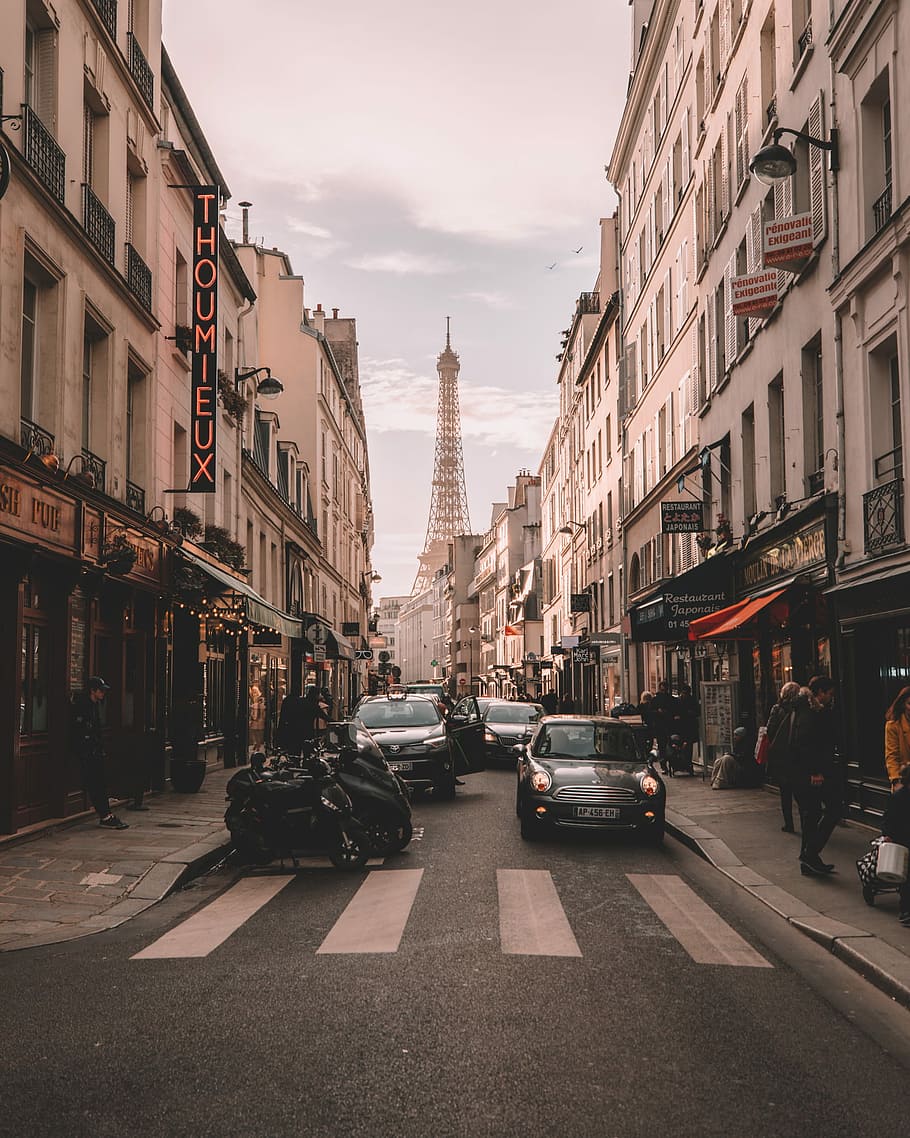 vehicles travelling on road surrounded by buildings during daytime, street photography of cars between buildings, HD wallpaper