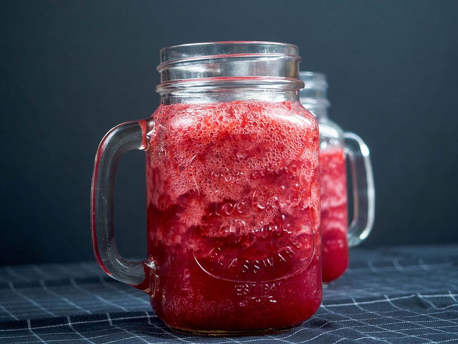 Closeup Photography of Two Clear Glass Jar Filled With Red Liquid on Top of Blue and White Tattersal Textile HD wallpaper