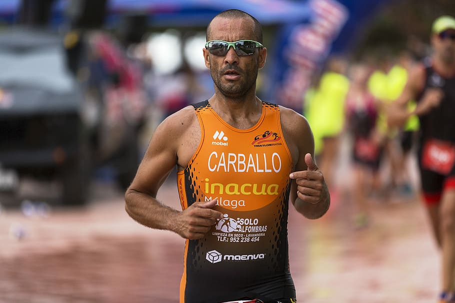 man wearing orange tank top and gray framed sport sunglasses, man wearing sports top in selective focus photography HD wallpaper
