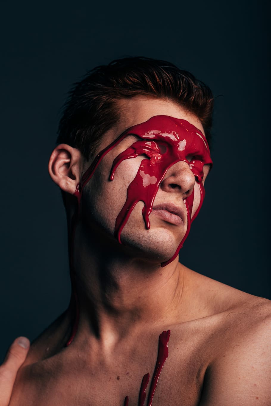 photo of man's face, man with red paint on face covered his eyes photo