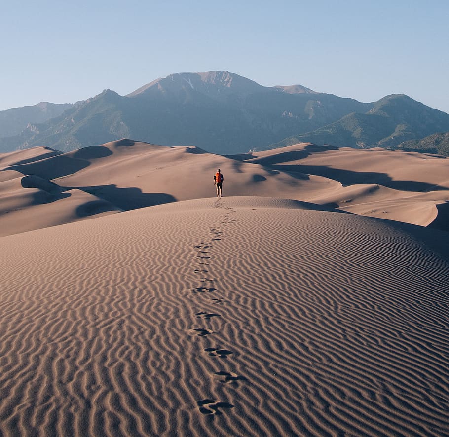 person walking on sand dunes leaving footprint trails behind, man standing on ground covered with sand, HD wallpaper