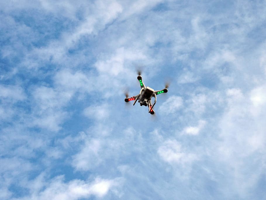 white low-angle photography of multicolored quadcopter on mid air under white clouds and blue sky during daytime HD wallpaper