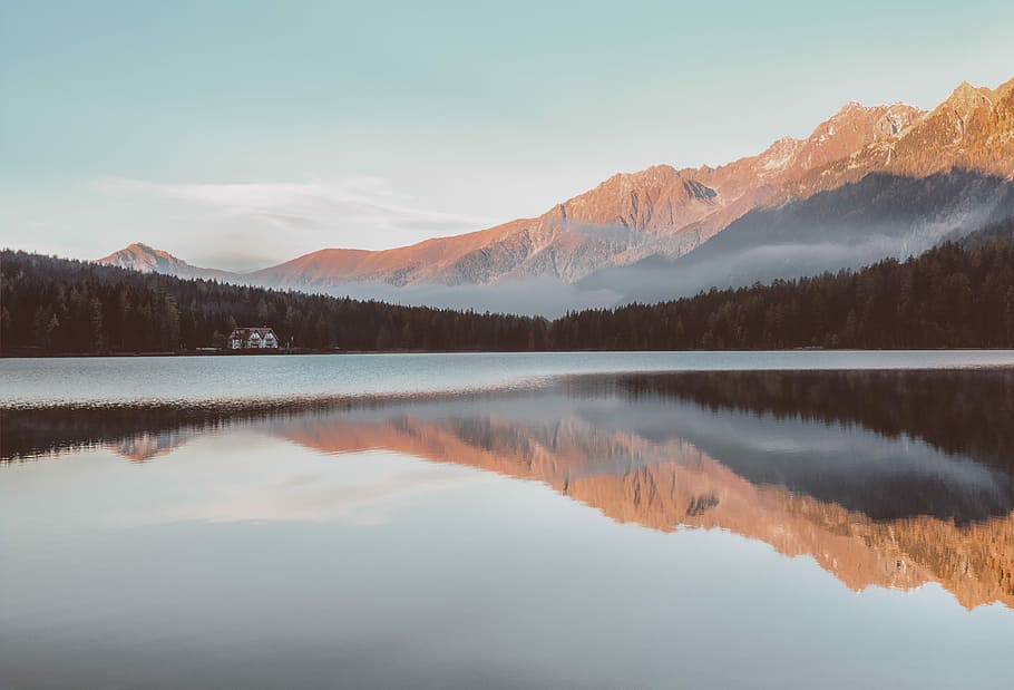 house near the forest and lake with mountains at the distance during day, panoramic photo of body of water HD wallpaper