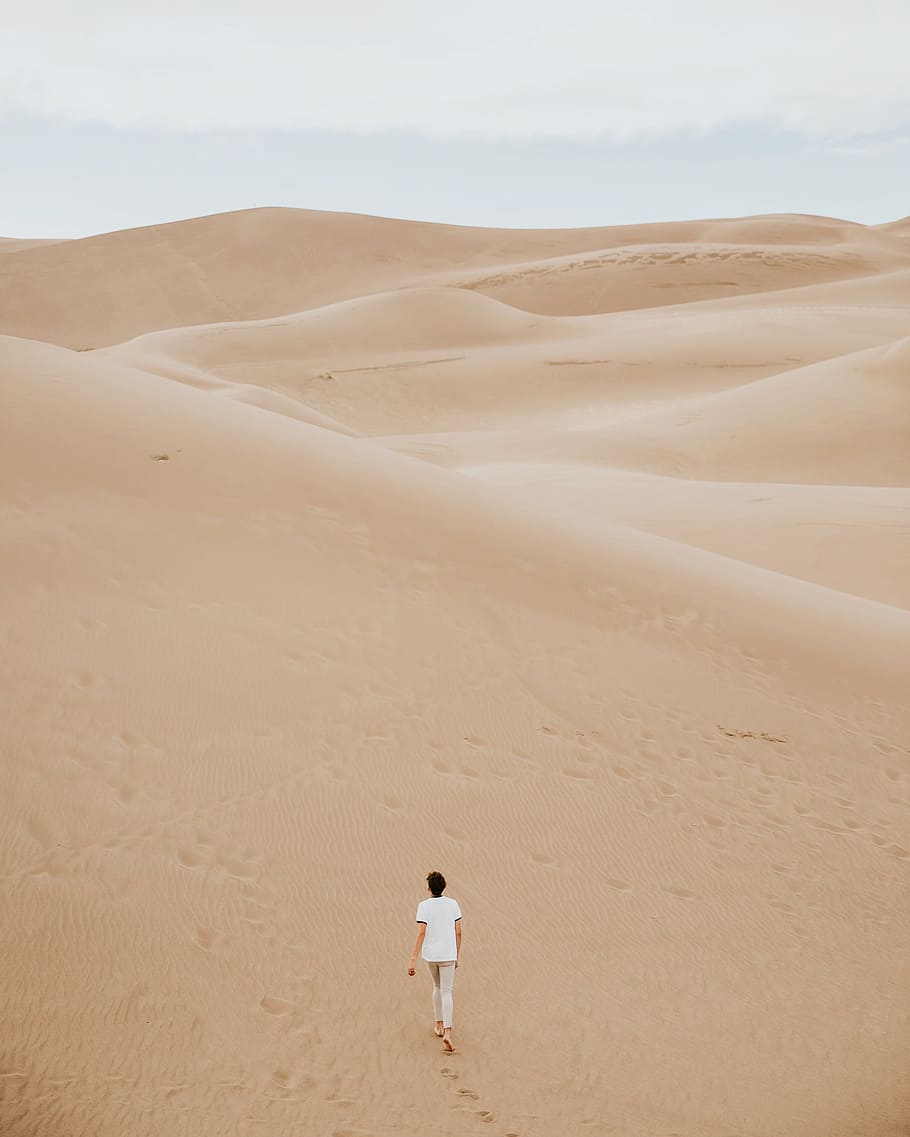 person walking on sand dune, man in white shirt walking on desert HD wallpaper