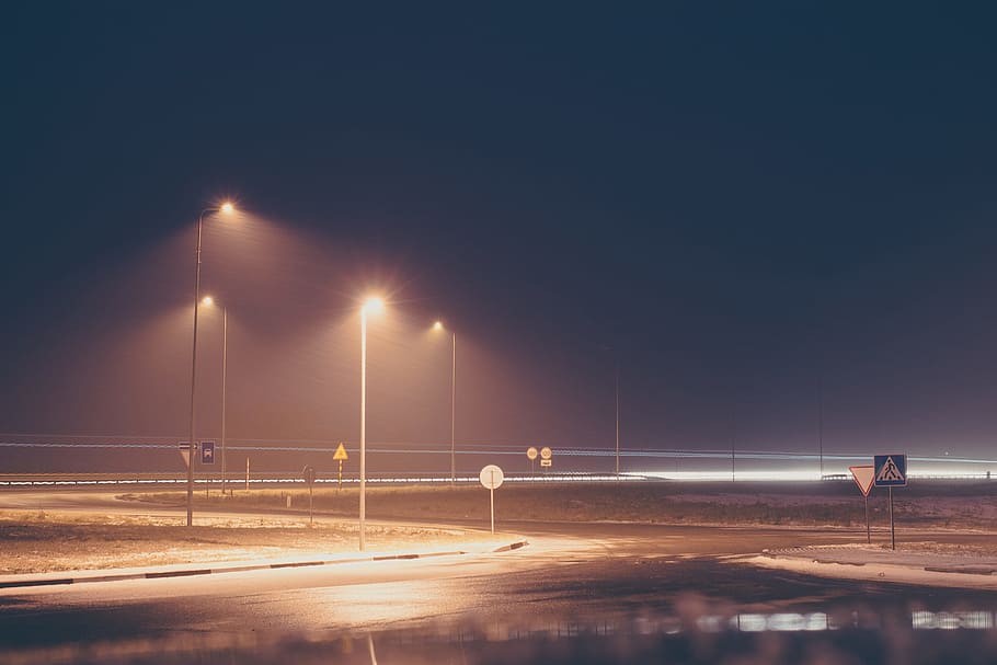 concrete road with turned on post lamp lights at nighttime, lighted utility post, HD wallpaper
