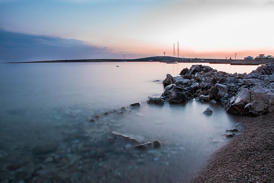 calm lake beside rock formation at daytime, rocks near water HD wallpaper