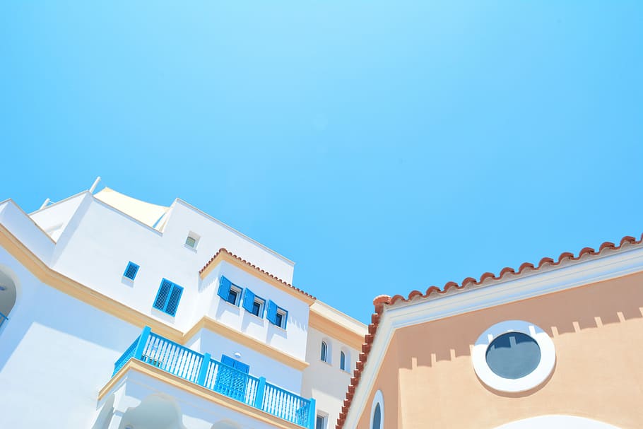 white and orange building, low angle photo of white and blue concrete house under blue clouds at daytime HD wallpaper