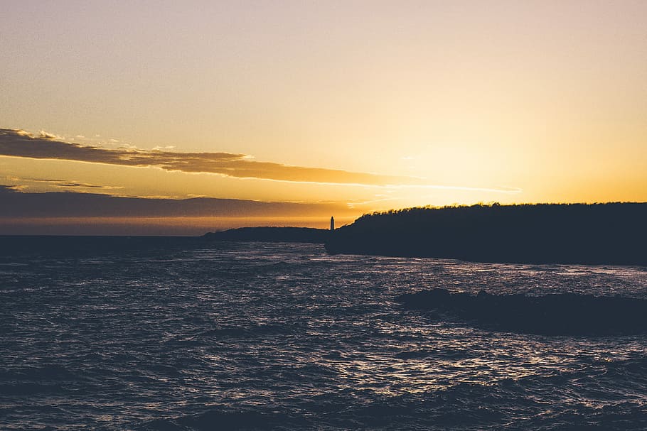 silhouette of cliff and body of water, body of water beside mountains in sunset HD wallpaper