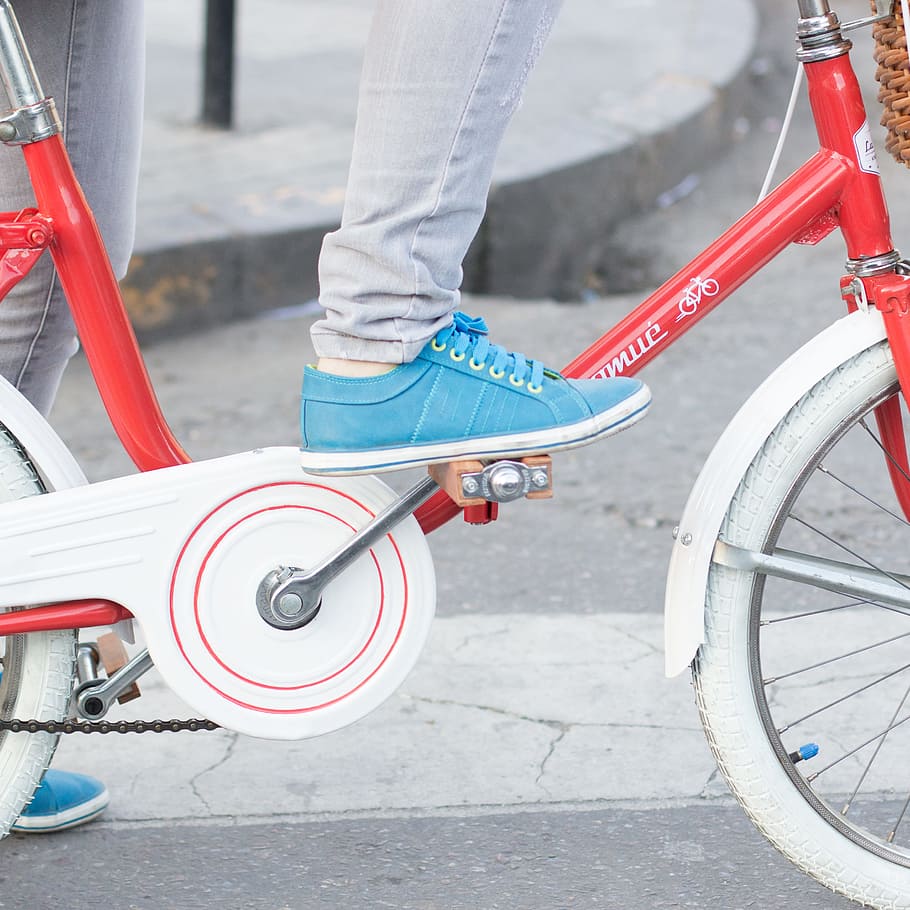 person riding red and white dutch bike, white and red city bicycle on road during daytime