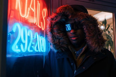 man in black full-zip hoodie leaning on neon light signage, man standing near turned on neon signage HD wallpaper