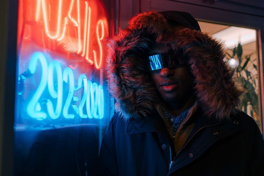 man in black full-zip hoodie leaning on neon light signage, man standing near turned on neon signage HD wallpaper