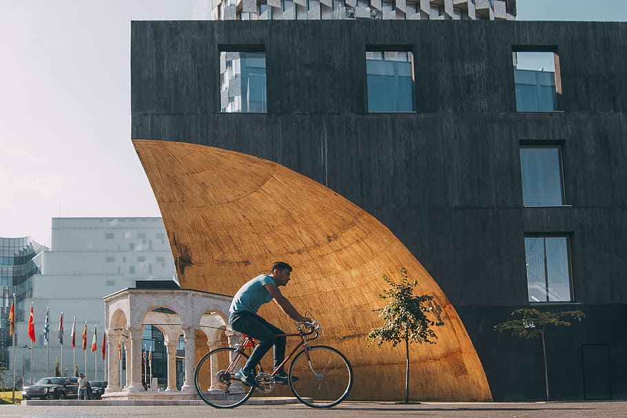 man riding bicycle near building, man riding on bike, person