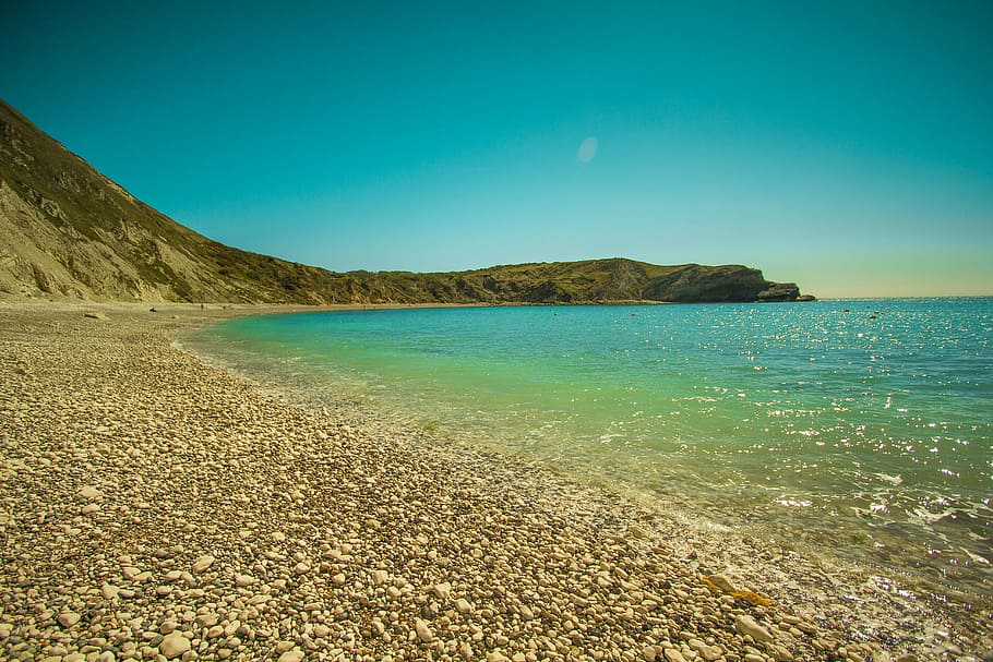 body of water under blue skies during day time, lulworth cove