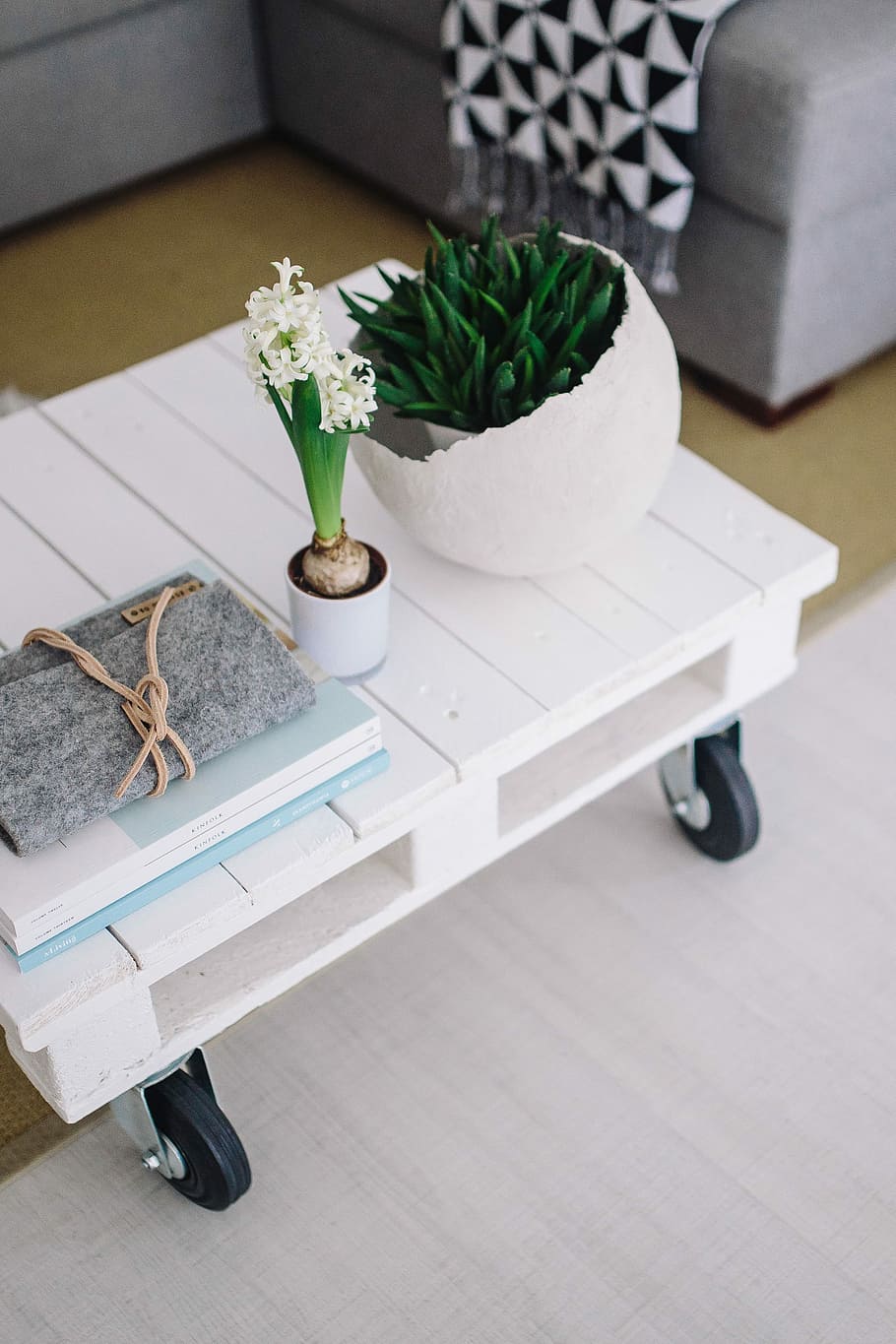 Small wooden table with a potted plant and a grey wallet, magazines