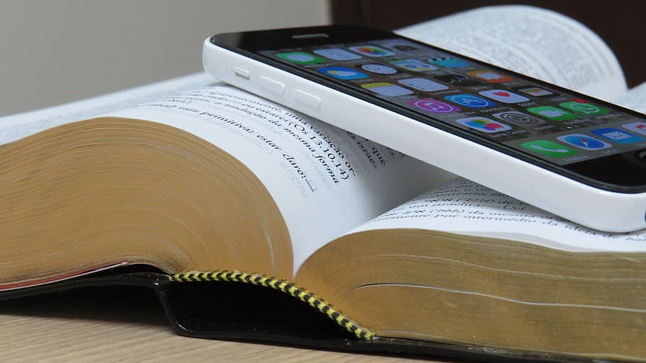 white iPhone 5c on top of open book, bible, cellular, technology