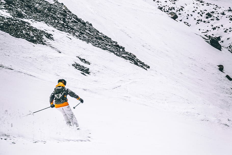 person skiing on snow at daytime, person skiing on mountain near rocks HD wallpaper