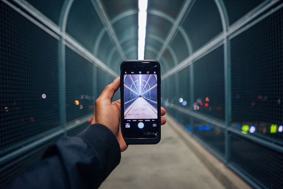 person holding phone showing empty tunnel, person holding smartphone showing empty bridge HD wallpaper