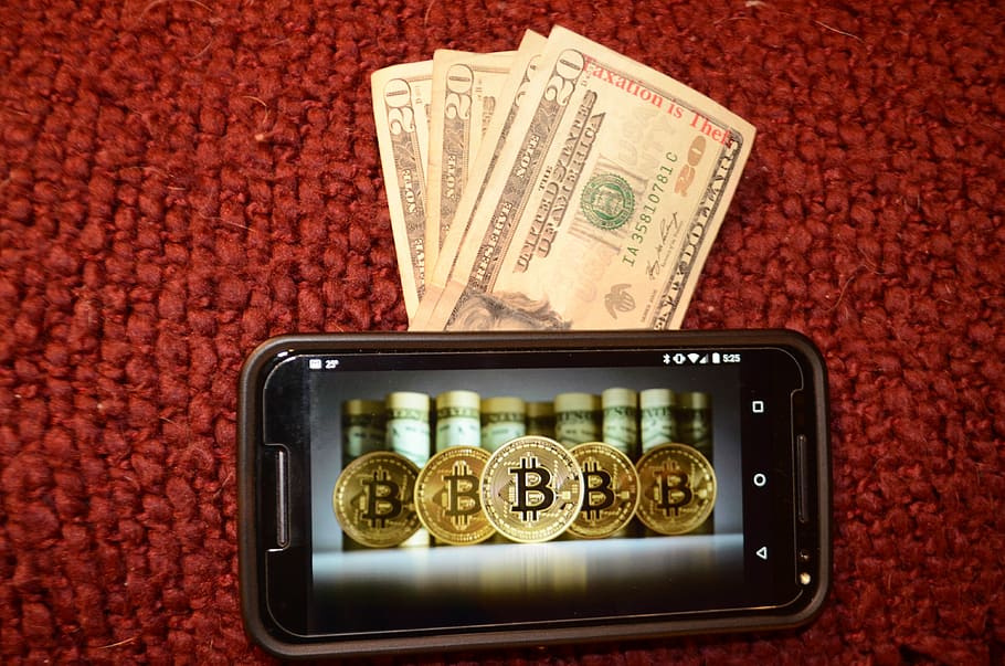 black Android smartphone and dollar banknotes, bitcoin, taxation is theft