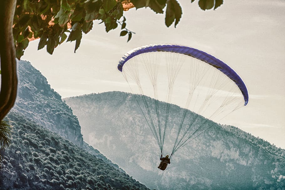 person on parachute near mountain, person paragliding above mountain HD wallpaper