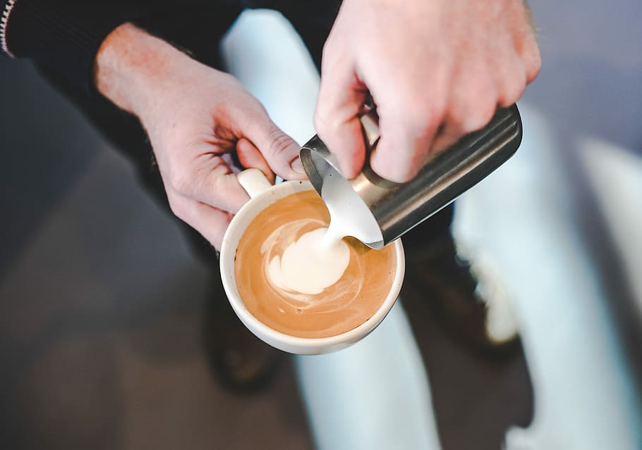 person pouring milk in coffe, person holding white ceramic mug with coffee mixing milk HD wallpaper