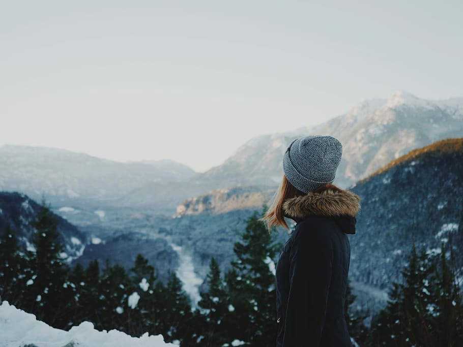 woman standing on snowfield, woman wearing grey knit cap standing on hill facing towards glacier mountain HD wallpaper