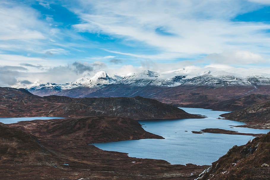 body of water under blue sky, mountain surrounded by body of water HD wallpaper