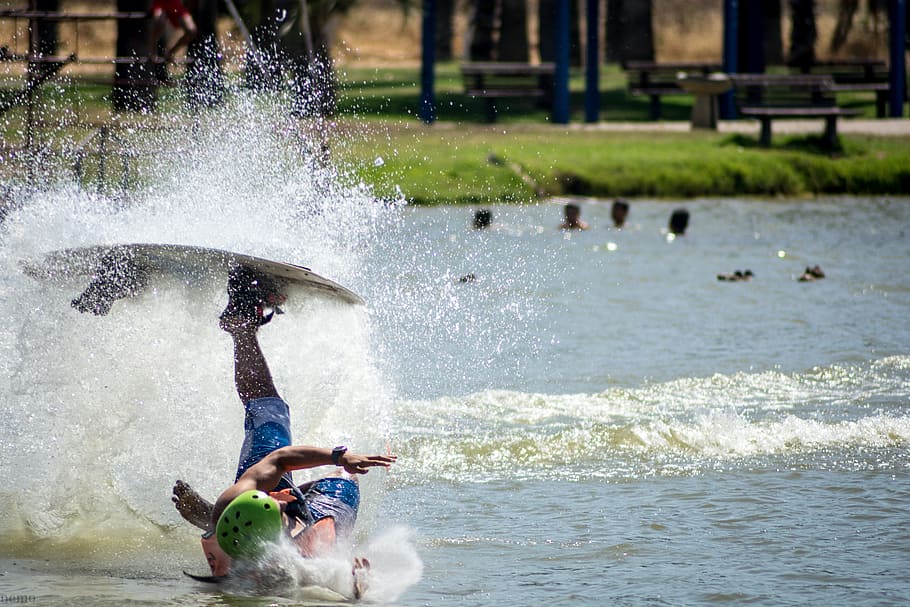 person hitting body of water upside down while his left foot on wakeboard