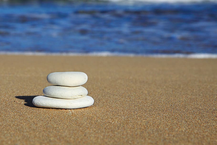 close up photo of stack of white stones, balance, beach, blue