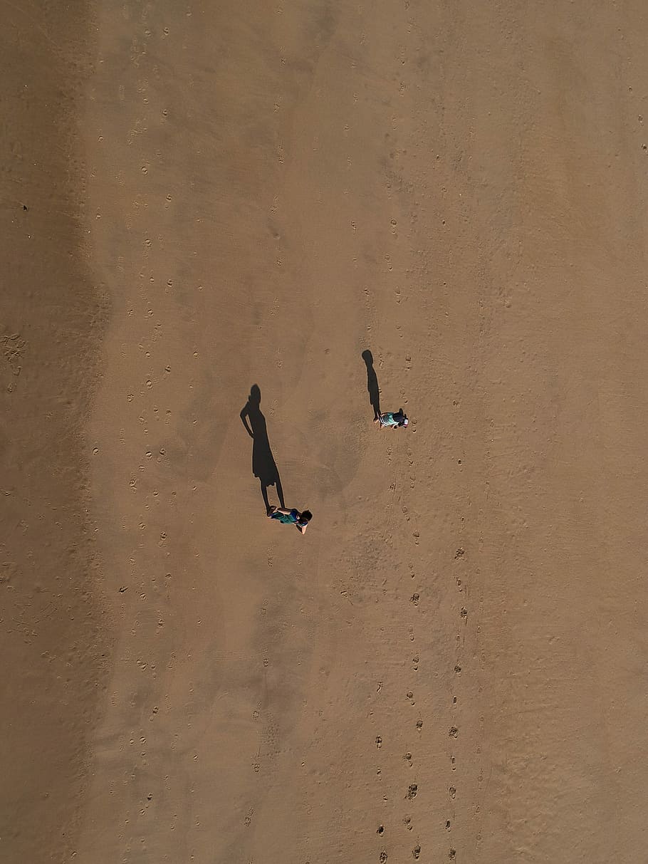 two person standing on desert at daytime, aerial photo of two person walking during daytime HD wallpaper