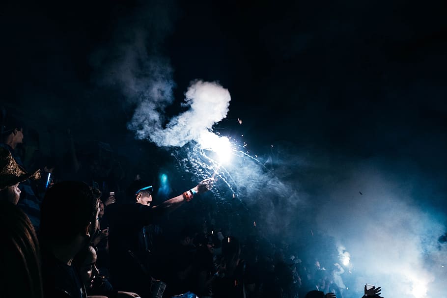 person playing with fireworks, person raising white flare with smoke