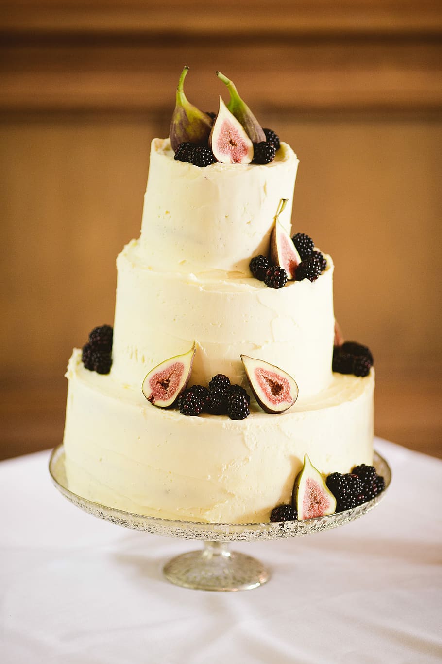 dragon fruit cake on top of table, white 3-layer cake, figs, blackberry