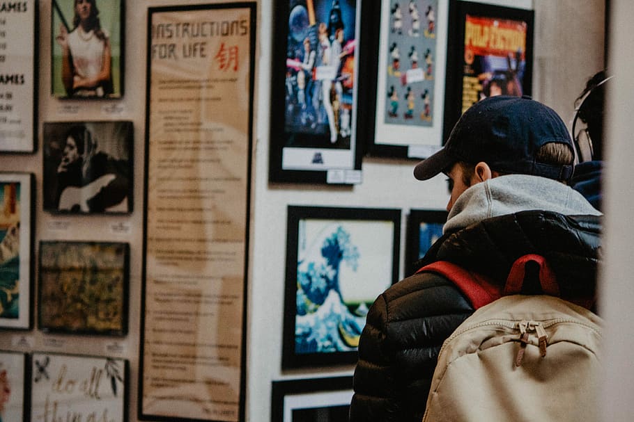 person wearing black bubble jacket watching wall posters, man looking at posters on wall HD wallpaper