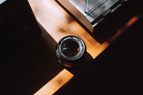 black DSLR camera lens on brown wooden table, black camera zoom lens on table HD wallpaper