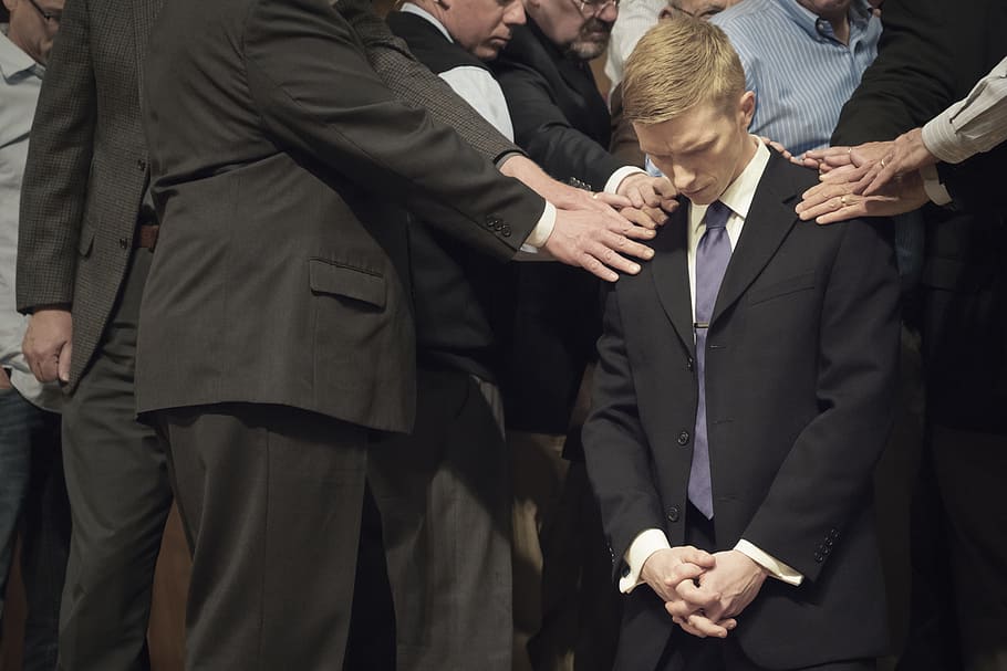 man bowing his head on another man, people holding man's shoulder that kneels HD wallpaper