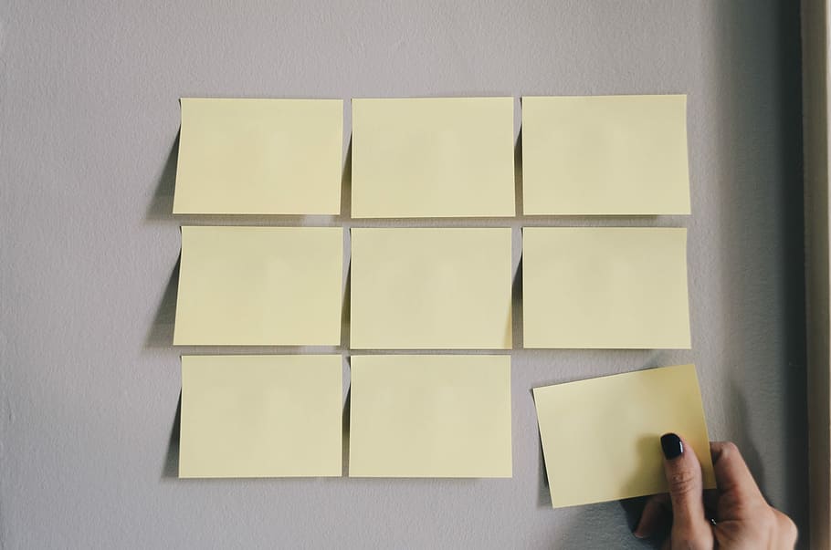 six white sticky notes, person holding yellow sticky note, paper