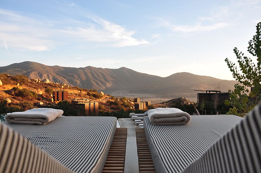 sunloungers fronting buildings near mountain, two white towels on textiles HD wallpaper