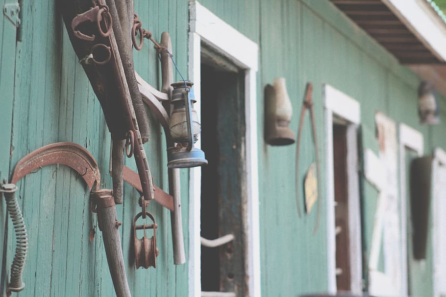blue kerosene lamp hanged on wall rack, brown scythe on wall HD wallpaper