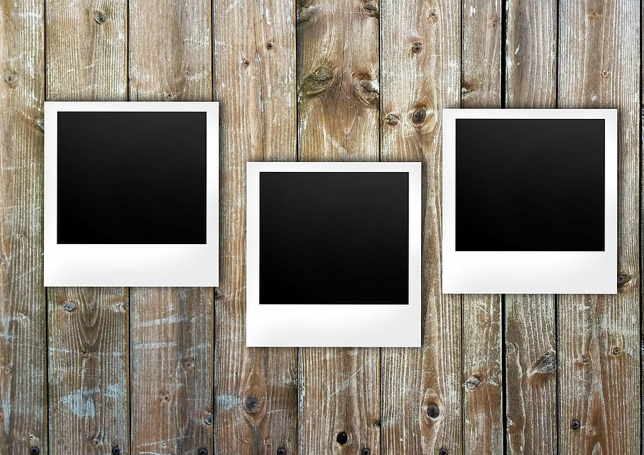 three white wooden frames on wall, polaroid, boards, notes, list