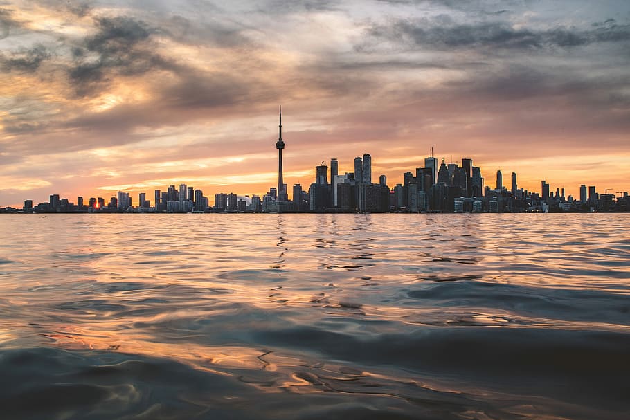 body of water under white cloudy sky, skyscrapers near body of water HD wallpaper