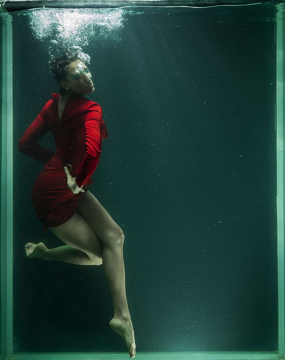 woman wearing red long-sleeved mini dress in water, underwater