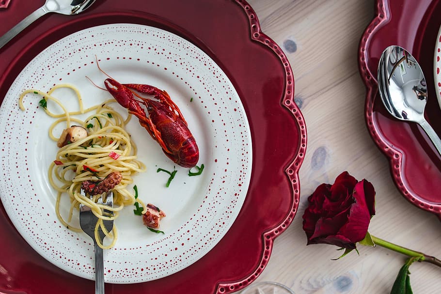 Fancy dinner with seafood pasta, crayfish and red wine by the table decorated with roses HD wallpaper