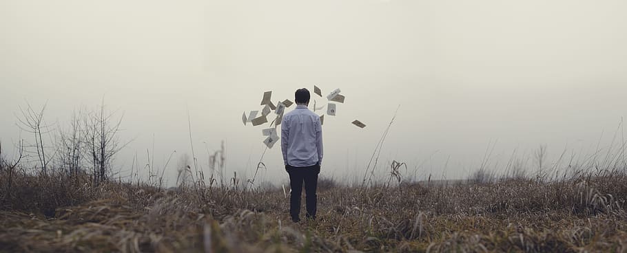 man standing on grass, person in white shirt standing on dried grass field during cloudy weather HD wallpaper