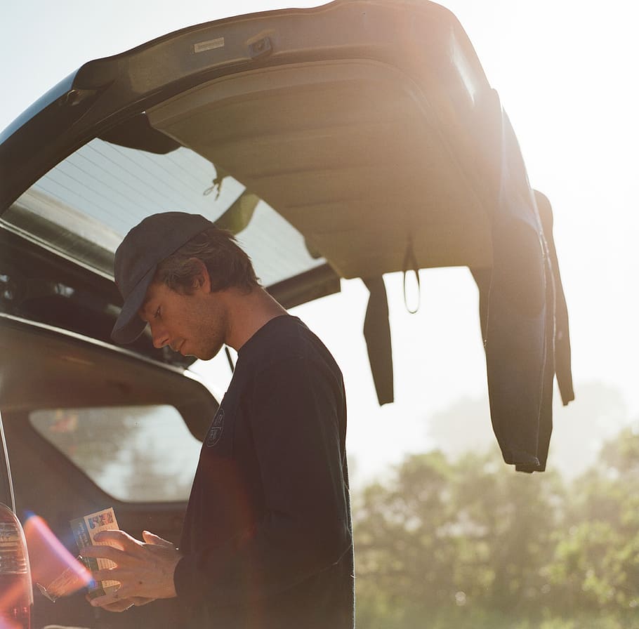 man in black sweater standing on the back of the vehicle, portrait HD wallpaper