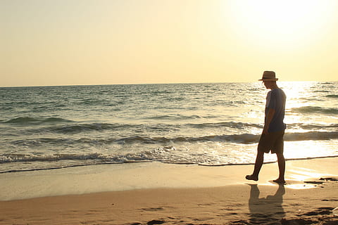 silhouette photography of person in blue shirt and beige fedora cap standing on seashore during golden hour HD wallpaper