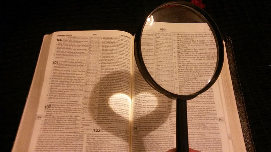 person holding black handled magnifying glass near book page, HD wallpaper