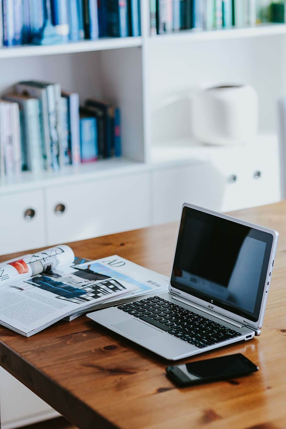 Silver laptop with various items on a table, magazines, computer HD wallpaper